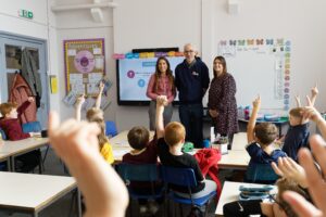 MyBnk trainer with Wales & West Utilities partners smiling in a primary school classroom with children