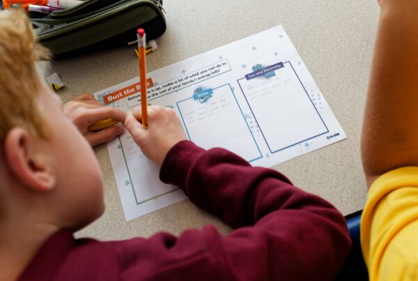 Primary school child writing on a MyBnk worksheet in a classroom