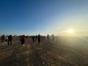 Crowds of runners approaching the start line of the Cairo Half Marathon, walking through the desert towards the pyramids of Giza