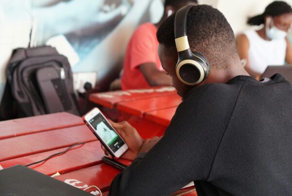 Young person with headphones on sat at a table looking at mobile phone